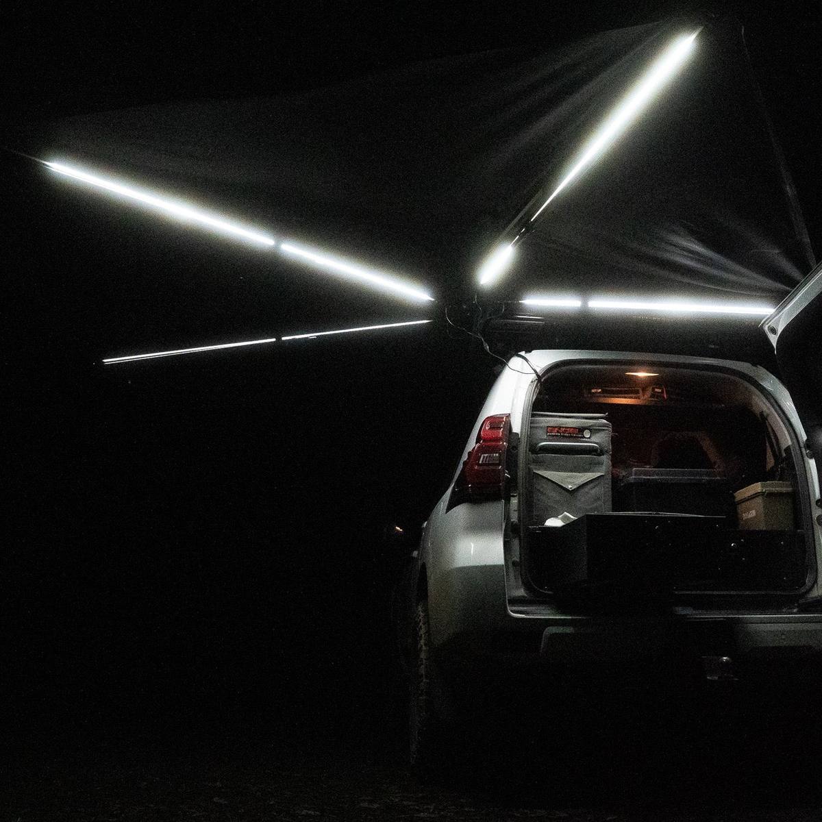Iron Element 270 awning LED strip lighting on every arm lit at night beside the vehicle's rear cargo area