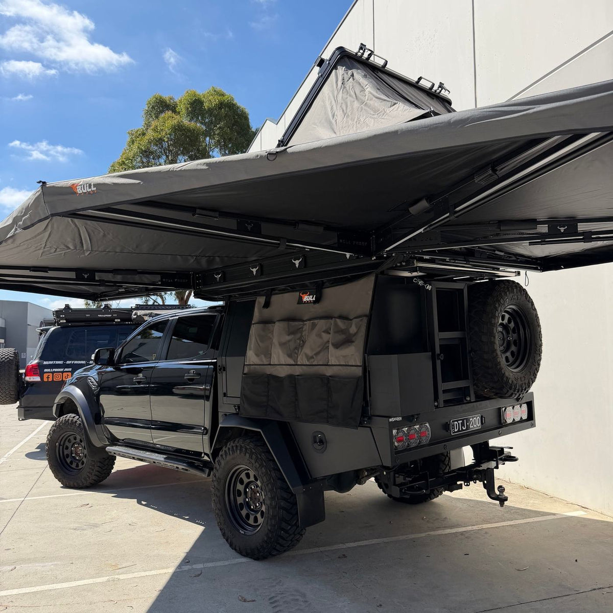 Iron Element 270 XL awning mounted over a black tray-back ute with rooftop tent in daylight